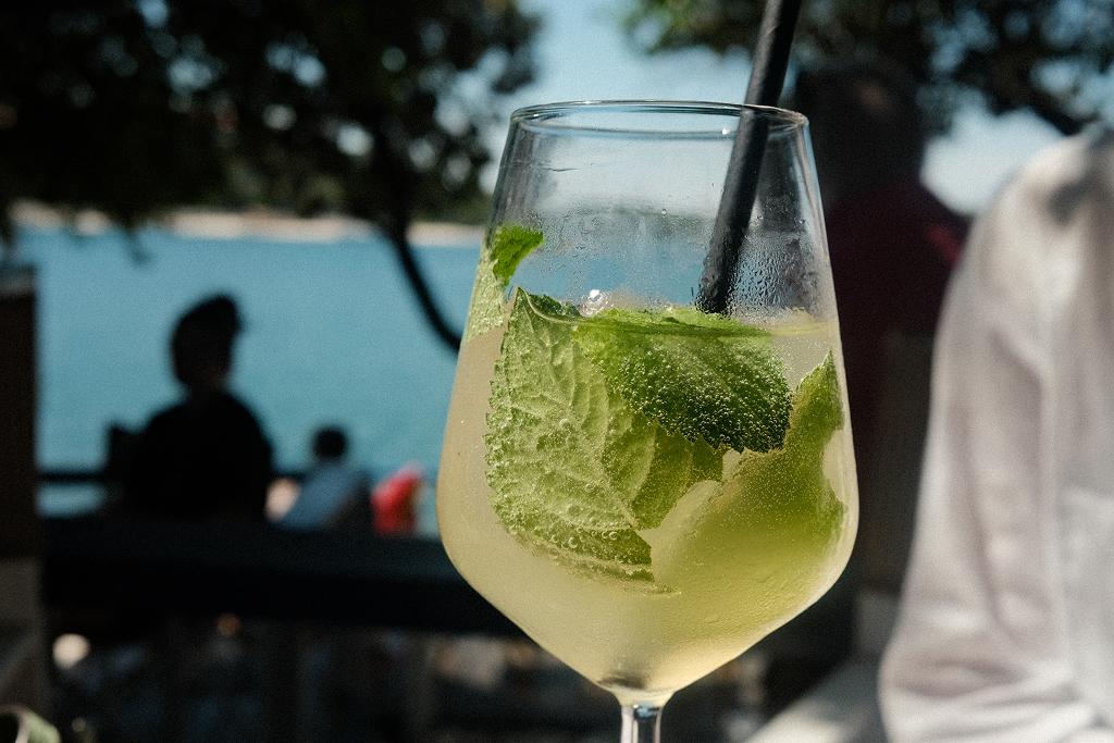 A glass with mint and a straw, on a table by a lake
