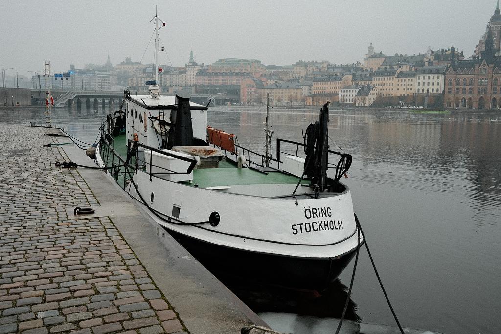 A white boat moored on a cobbled quay on a misty morning